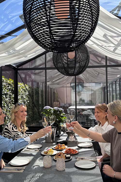Glada gäster som skålar i glas under en kväll i orangeriet på Malmö Arena Hotel – en stämningsfull plats för fest och samvaro.