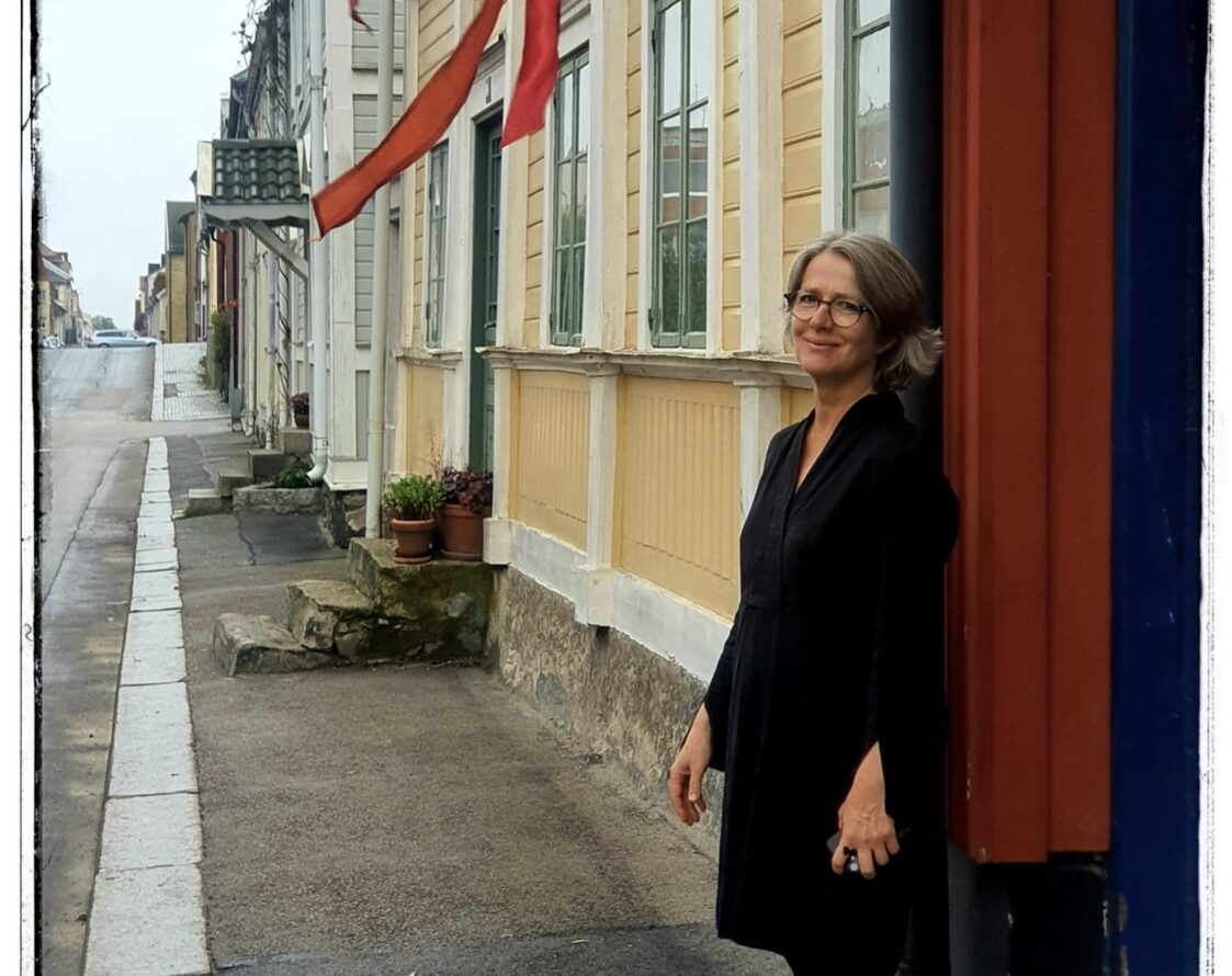 Konstnären Marie Caldemo står vid en husvägg