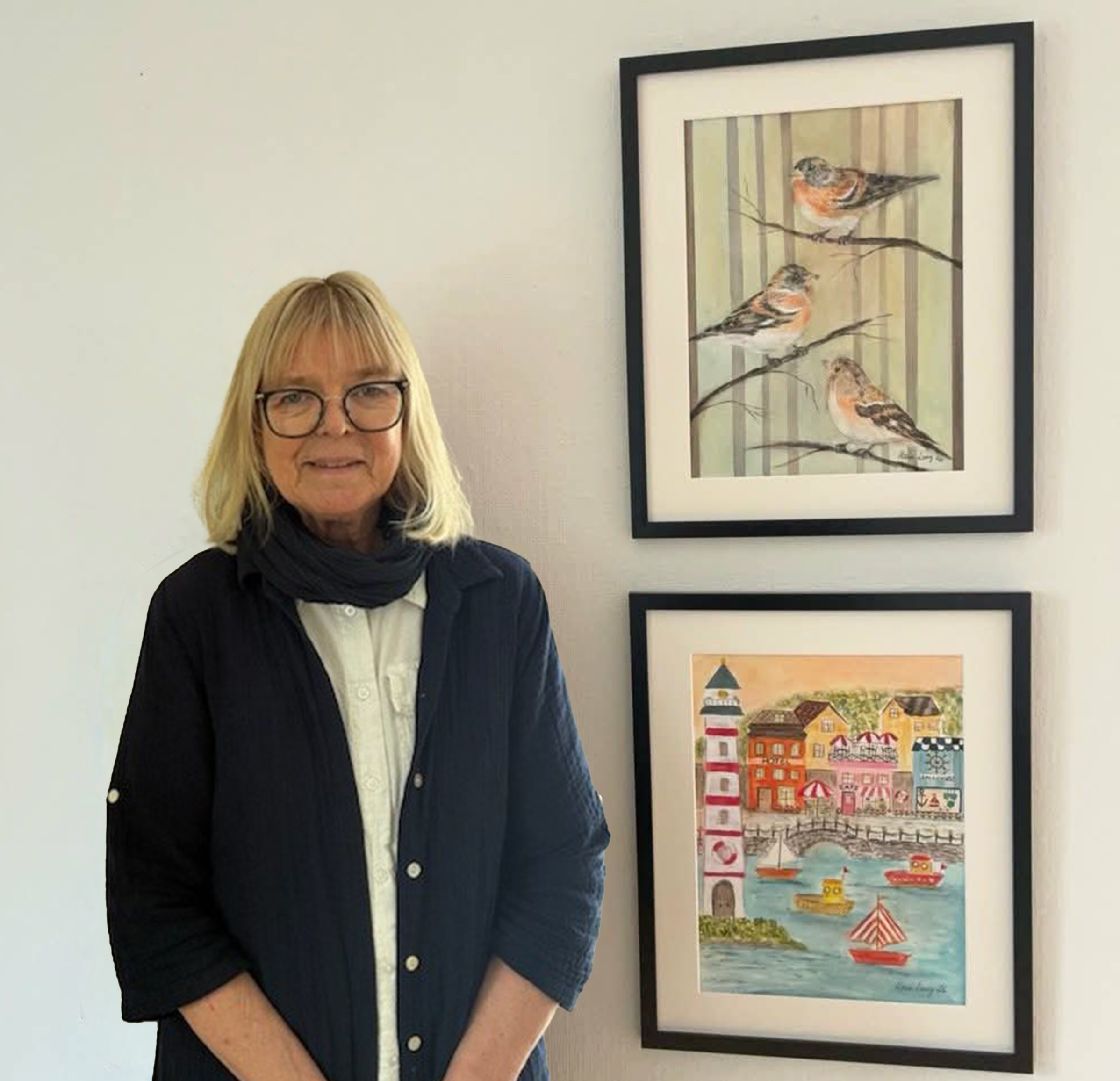 Maria Lang bredvid två av sina verk: ett föreställer fåglar, ett föreställer en kuststad